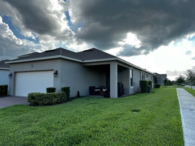9318 Mclaren Aly, Winter Garden, FL 34787 - view of side of home featuring stucco siding, a yard, an attached garage, and driveway