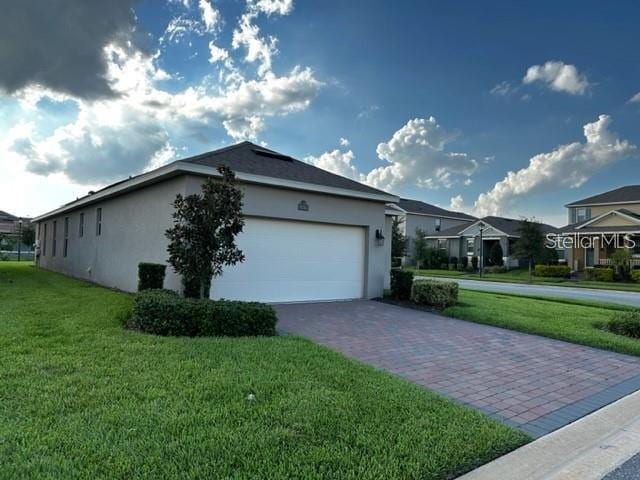 9318 Mclaren Aly, Winter Garden, FL 34787 - view of side of home with stucco siding, driveway, an attached garage, and a lawn