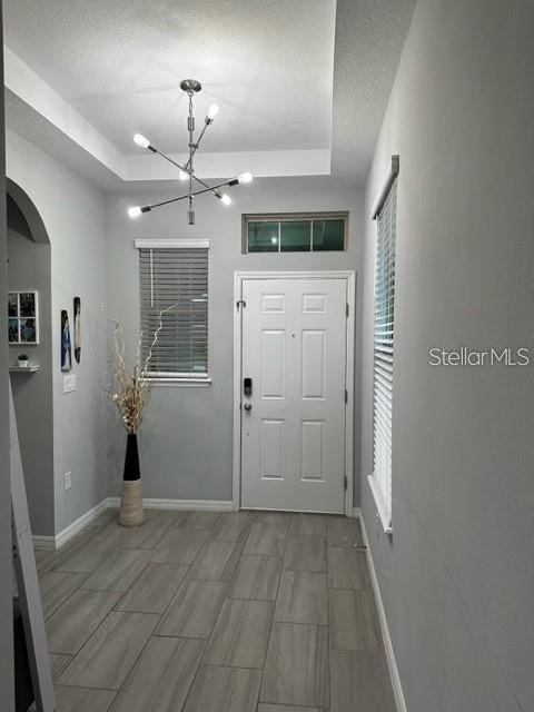 9318 Mclaren Aly, Winter Garden, FL 34787 - foyer with a raised ceiling, a chandelier, baseboards, and arched walkways