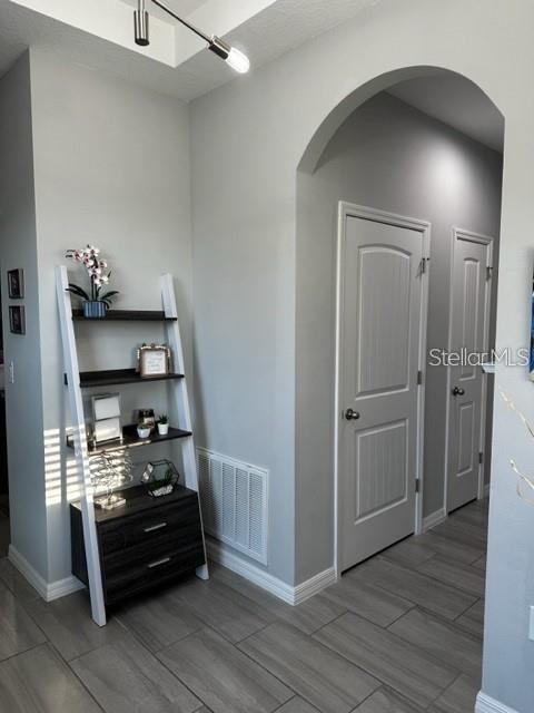 9318 Mclaren Aly, Winter Garden, FL 34787 - corridor featuring arched walkways, baseboards, and wood tiled floors