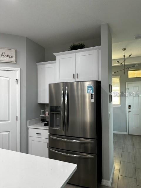 9318 Mclaren Aly, Winter Garden, FL 34787 - kitchen featuring stainless steel refrigerator with ice dispenser, light countertops, white cabinetry, and baseboards