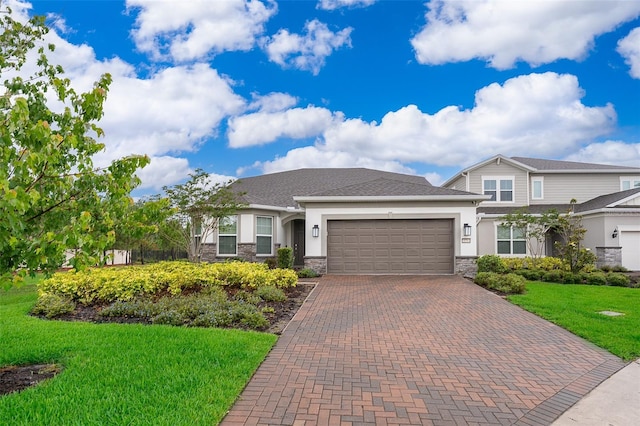 view of front of house with stucco siding, stone siding, an attached garage, decorative driveway, and a front yard