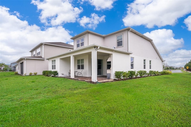 rear view of house featuring a patio, a lawn, and stucco siding