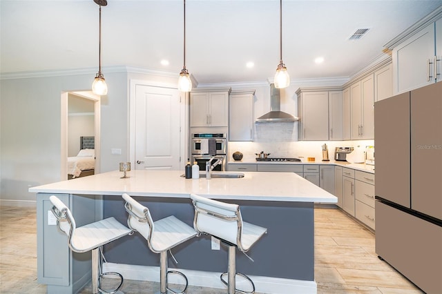 kitchen featuring appliances with stainless steel finishes, wall chimney range hood, gray cabinetry, crown molding, and recessed lighting
