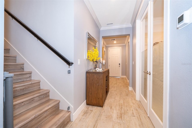corridor with stairway, light wood-type flooring, ornamental molding, and baseboards