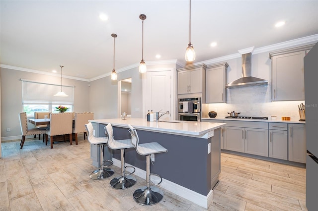 kitchen featuring wall chimney exhaust hood, gray cabinetry, double oven, light countertops, and ornamental molding