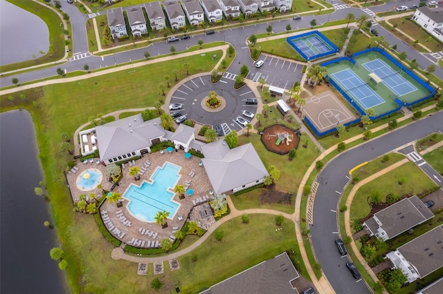 aerial perspective of suburban area with a pool and a nearby body of water
