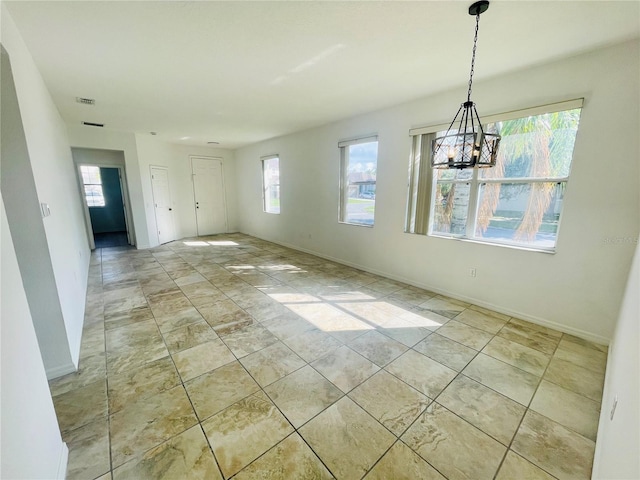 unfurnished dining area featuring healthy amount of natural light, a chandelier, and baseboards