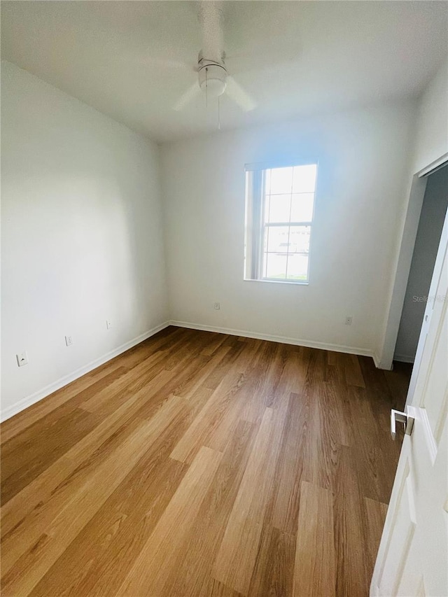 spare room with light wood finished floors, baseboards, and a ceiling fan
