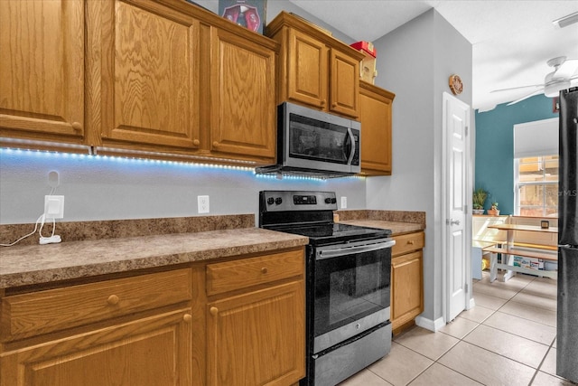 4981 Alita Ter, Saint Cloud, FL 34769 - kitchen with appliances with stainless steel finishes, light tile patterned flooring, brown cabinetry, and ceiling fan