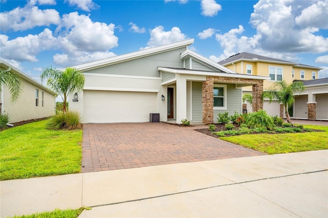 view of front facade featuring decorative driveway, a garage, a front lawn, and stucco siding