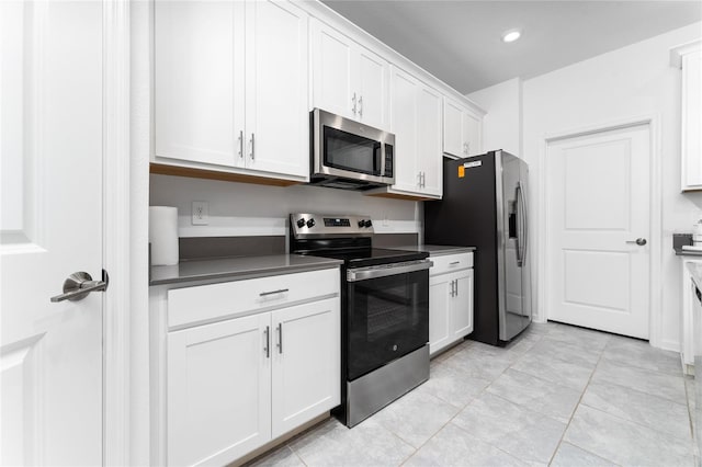 kitchen featuring appliances with stainless steel finishes, white cabinets, dark countertops, light tile patterned floors, and recessed lighting