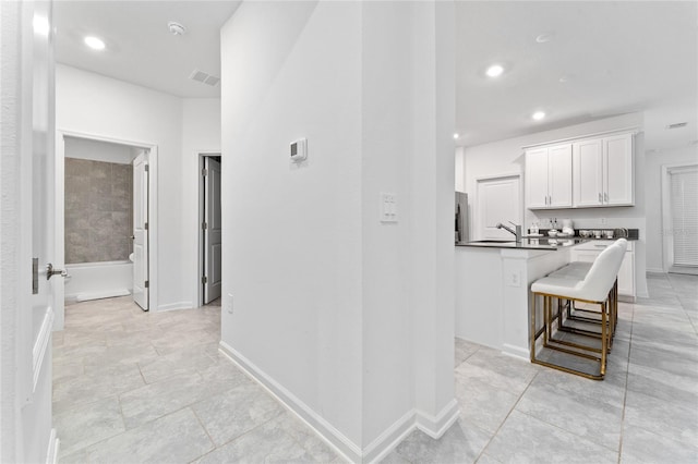 corridor featuring recessed lighting, light tile patterned floors, and baseboards