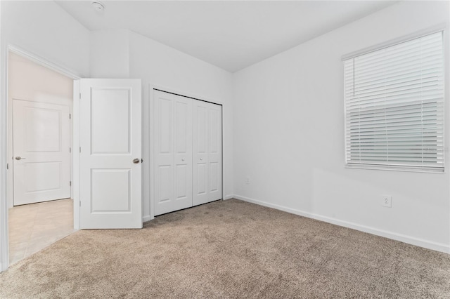unfurnished bedroom with carpet floors, baseboards, and a closet