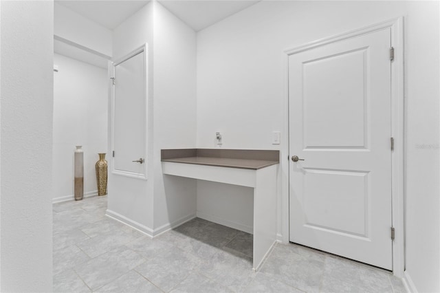 hallway with a desk and baseboards