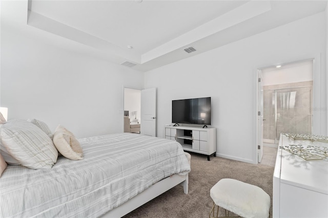 bedroom featuring light colored carpet, a raised ceiling, ensuite bathroom, and baseboards