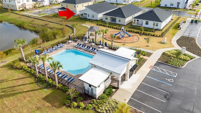 aerial perspective of suburban area featuring a pool area and a large body of water