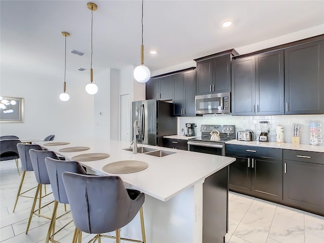 2970 Protagonist St, Kissimmee, FL 34746 - kitchen featuring appliances with stainless steel finishes, an island with sink, a breakfast bar, light countertops, and backsplash