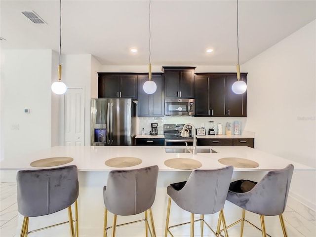 2970 Protagonist St, Kissimmee, FL 34746 - kitchen with appliances with stainless steel finishes, a sink, light countertops, a breakfast bar, and decorative light fixtures