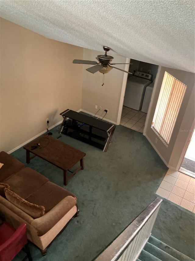 tiled living area featuring a textured ceiling, a ceiling fan, washer / clothes dryer, carpet flooring, and baseboards