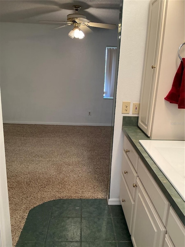 bathroom featuring ceiling fan, baseboards, and vanity