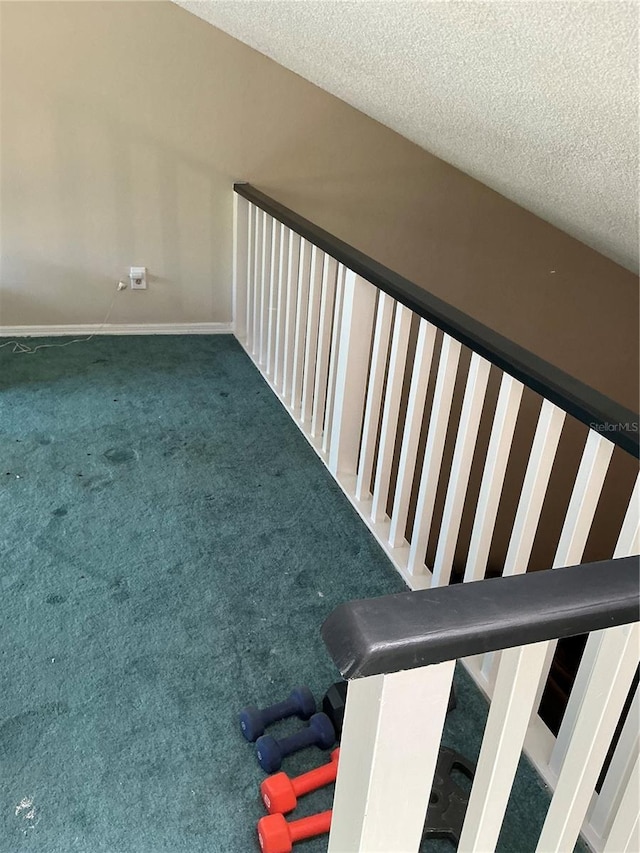 stairs with a textured ceiling, carpet, and baseboards