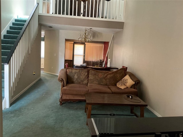 carpeted living area with stairway, baseboards, a chandelier, and a high ceiling