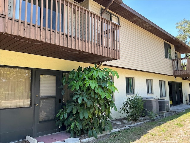 back of property featuring a balcony, stucco siding, and central AC