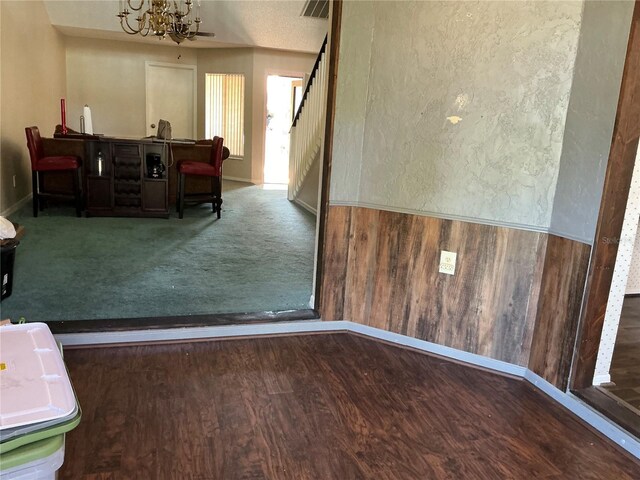 unfurnished dining area featuring a chandelier, wood finished floors, stairs, baseboards, and wainscoting
