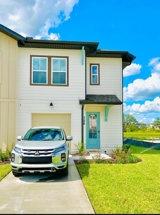 view of front of property featuring driveway, a front lawn, an attached garage, and board and batten siding