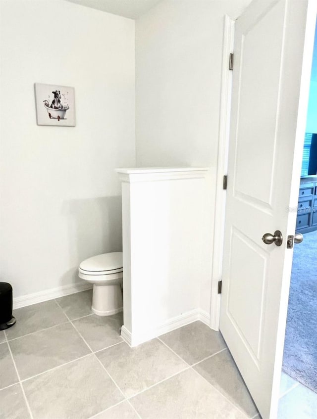 bathroom featuring tile patterned flooring, toilet, and baseboards