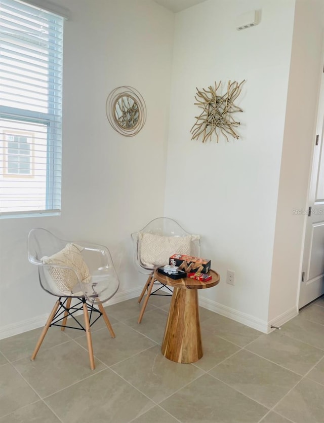 living area with healthy amount of natural light, tile patterned flooring, and baseboards