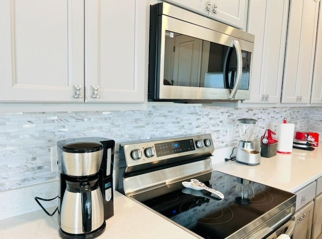 kitchen with stainless steel appliances, light countertops, backsplash, and white cabinetry