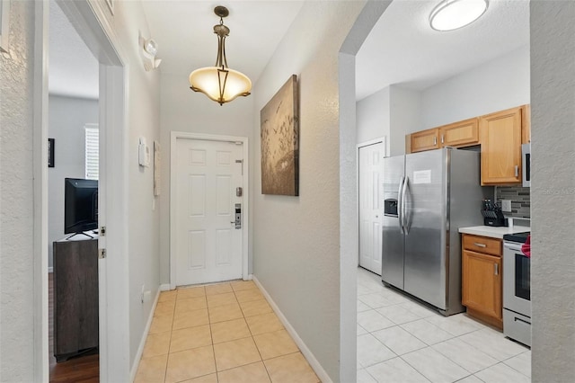 203 La Mirage St, Davenport, FL 33897 - kitchen featuring appliances with stainless steel finishes, light tile patterned flooring, light countertops, hanging light fixtures, and arched walkways