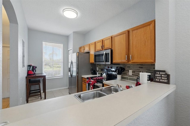203 La Mirage St, Davenport, FL 33897 - kitchen with stainless steel appliances, arched walkways, decorative backsplash, light countertops, and light tile patterned floors