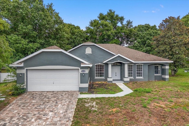 ranch-style home featuring stucco siding, an attached garage, and driveway