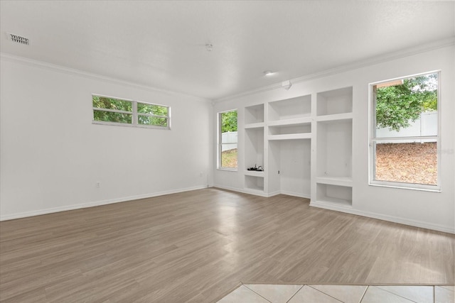unfurnished living room with crown molding, built in features, healthy amount of natural light, baseboards, and wood finished floors