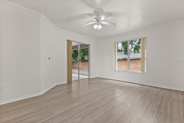 spare room featuring a ceiling fan, light wood finished floors, crown molding, and baseboards