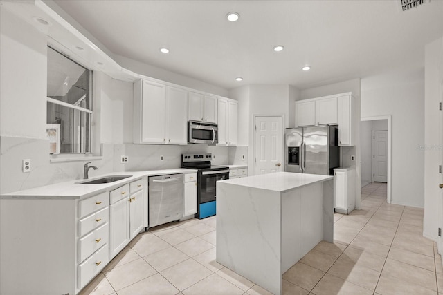 kitchen featuring appliances with stainless steel finishes, a sink, white cabinets, a center island, and light tile patterned flooring