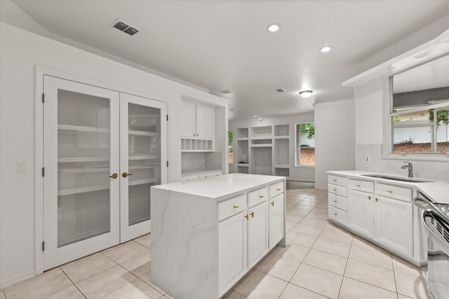 kitchen with a sink, white cabinets, electric range, light tile patterned flooring, and recessed lighting