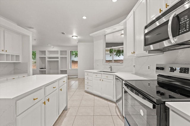 kitchen featuring stainless steel appliances, a sink, light tile patterned floors, white cabinetry, and recessed lighting