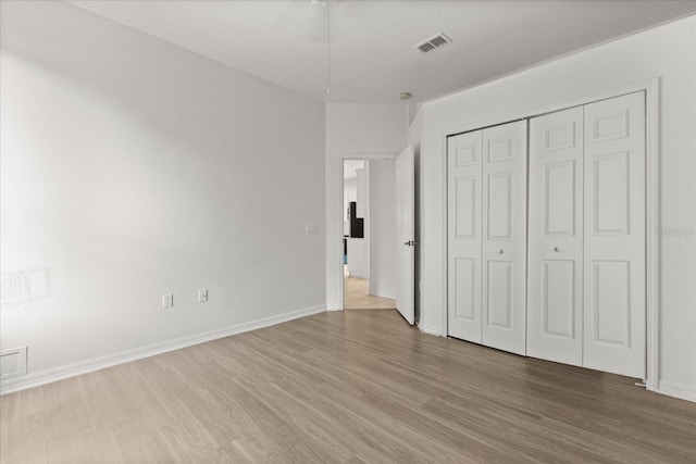 unfurnished bedroom featuring light wood finished floors, a closet, and baseboards