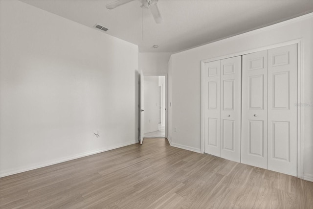 unfurnished bedroom with light wood-style flooring, a closet, baseboards, and a ceiling fan