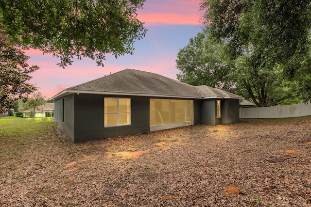 back of property with fence, a shingled roof, and stucco siding
