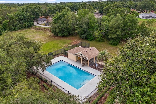 view of swimming pool with fence, a patio, and a view of trees