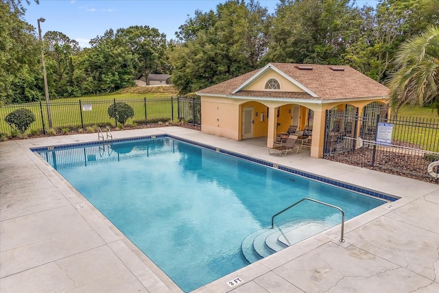 community pool with fence, a patio area, and view of scattered trees