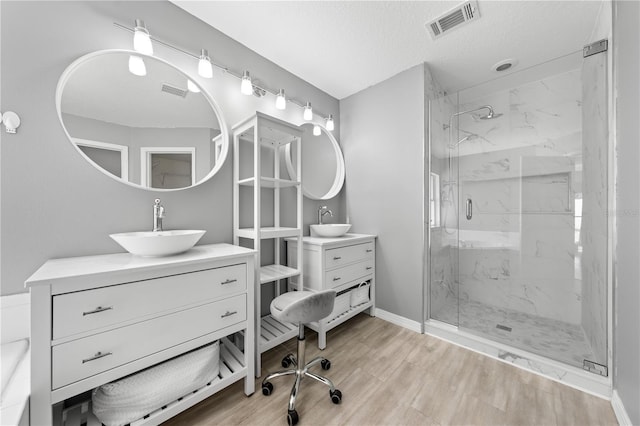 3203 Herons Point Cir, Kissimmee, FL 34741 - full bath with a marble finish shower, a textured ceiling, two vanities, wood finished floors, and baseboards