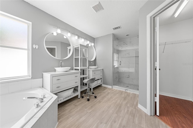 3203 Herons Point Cir, Kissimmee, FL 34741 - full bathroom featuring a stall shower, a bath, vanity, wood finished floors, and a walk in closet