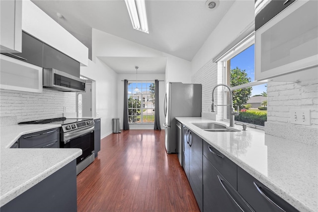 3203 Herons Point Cir, Kissimmee, FL 34741 - kitchen with appliances with stainless steel finishes, a sink, vaulted ceiling, decorative backsplash, and dark cabinetry