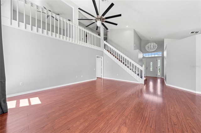 3203 Herons Point Cir, Kissimmee, FL 34741 - unfurnished living room featuring high vaulted ceiling, a chandelier, stairway, baseboards, and wood finished floors